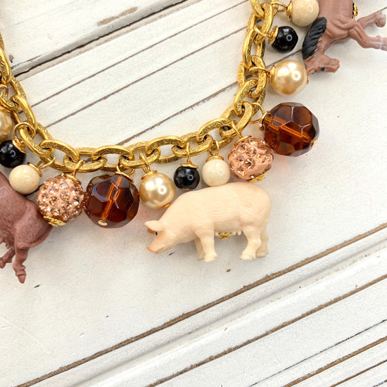 Miniature pig charm on a gold chain charm bracelet.