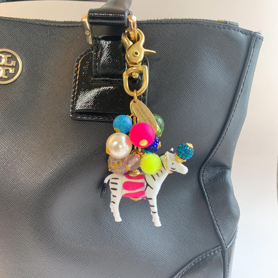 Colorful cute bag charm on a black handbag. Lenora Dame bag charms.