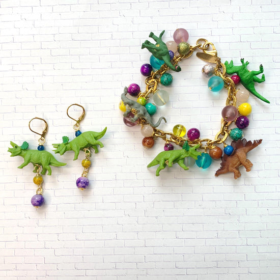 Triceratops earrings and a miniature dinosaur bracelet fill with dinosaur figurines and colorful beads wire wrapped to a gold bracelet chain.