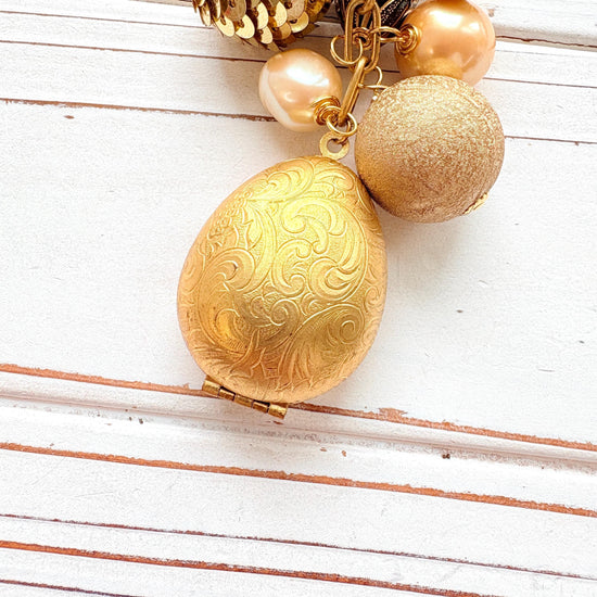 Up close of an egg shaped etched brass hinged photo locket.