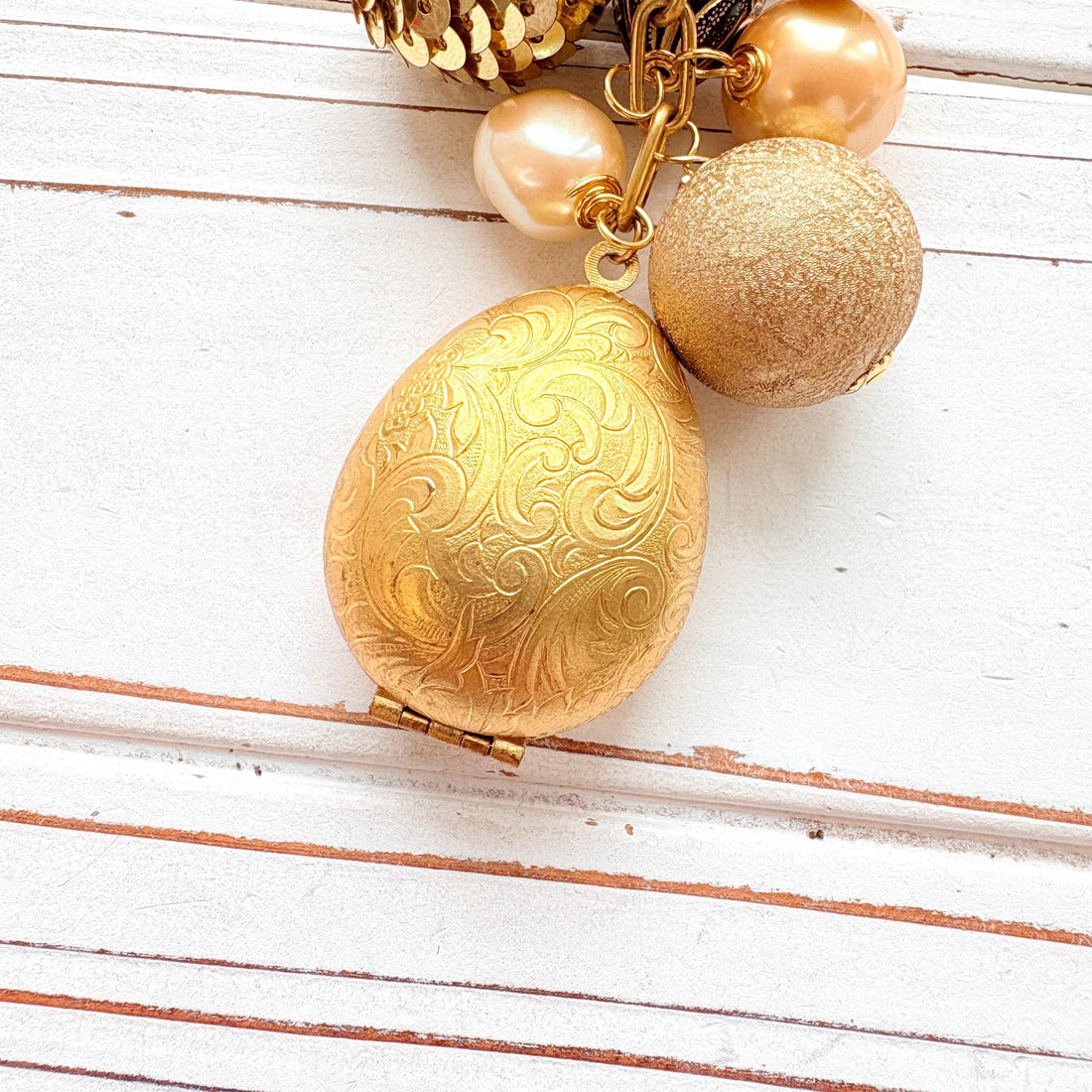 Up close of an egg shaped etched brass hinged photo locket.