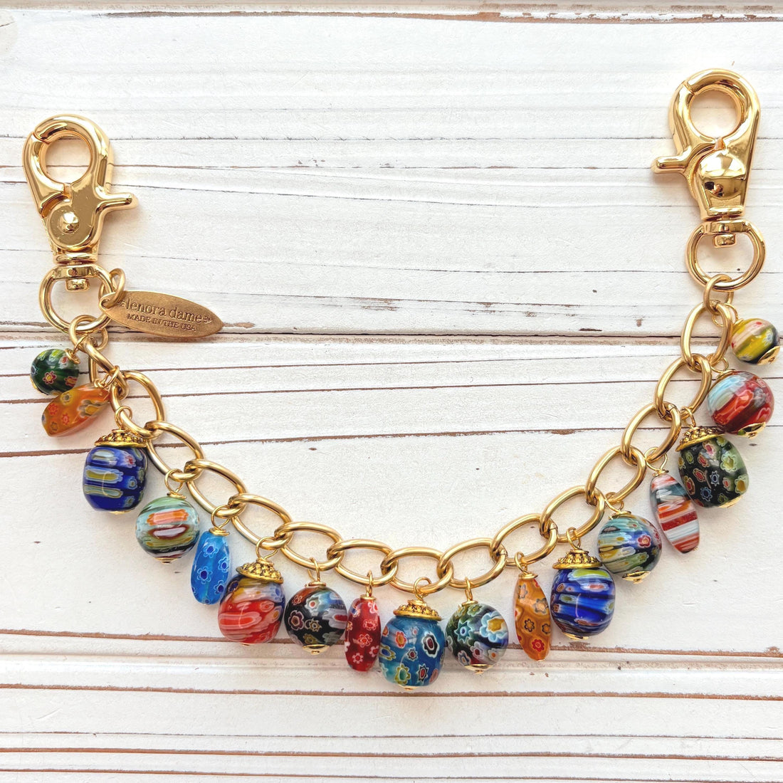 Assorted color and shaped floral glass millefiori glass beads dangling from a gold purse bag chain. Floral lampwork beads on a gold chain. Lenora Dame bag chain.