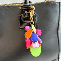 Colorful beaded bag charm with a mix of different shaped beads in a cluster under a gold trigger clasp with a gold oval charm that says Lenora Dame Made in USA. One round black and white zebra bead is among the beads. Lenora Dame bag charm.